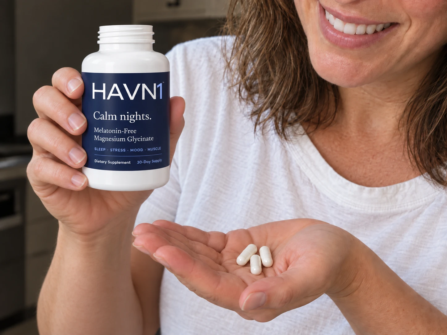 A woman holding an open HAVN1 bottle and three capsules in her palm